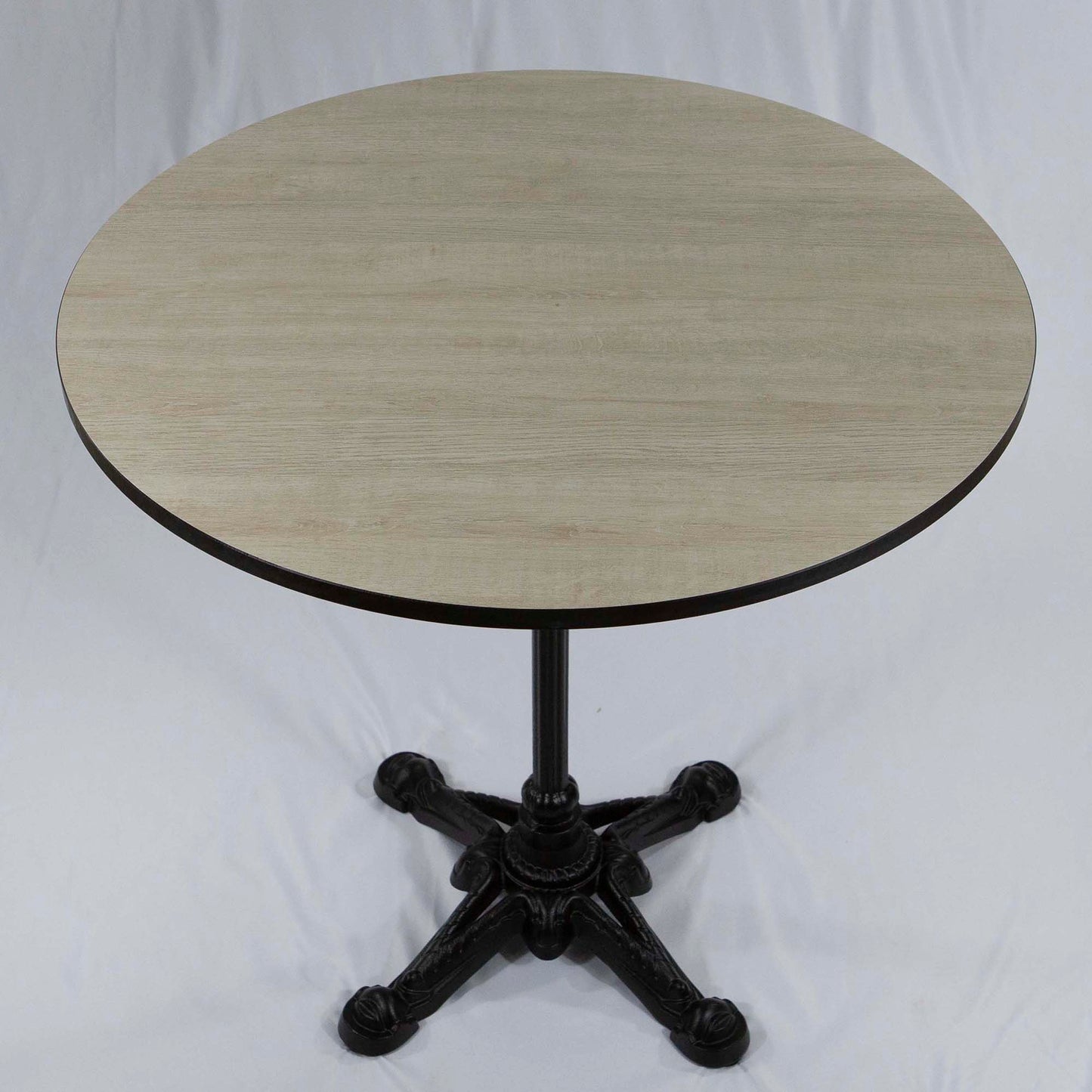 Round table with a light wooden top and black metal base on a white background