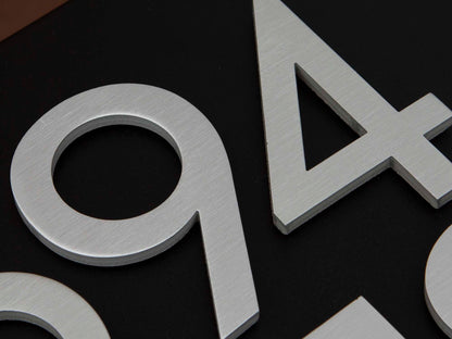 Close-up of brushed metal house numbers installed on HC139 black mailbox