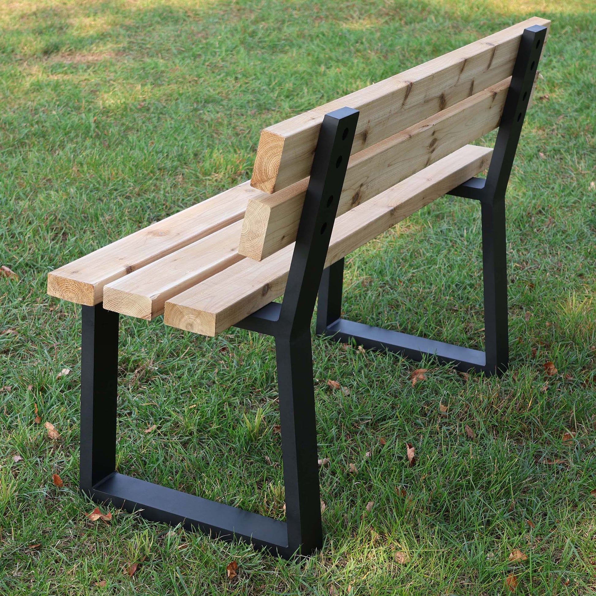 wooden bench supported by black trapezoid aluminum legs with integrated backrest outdoors

